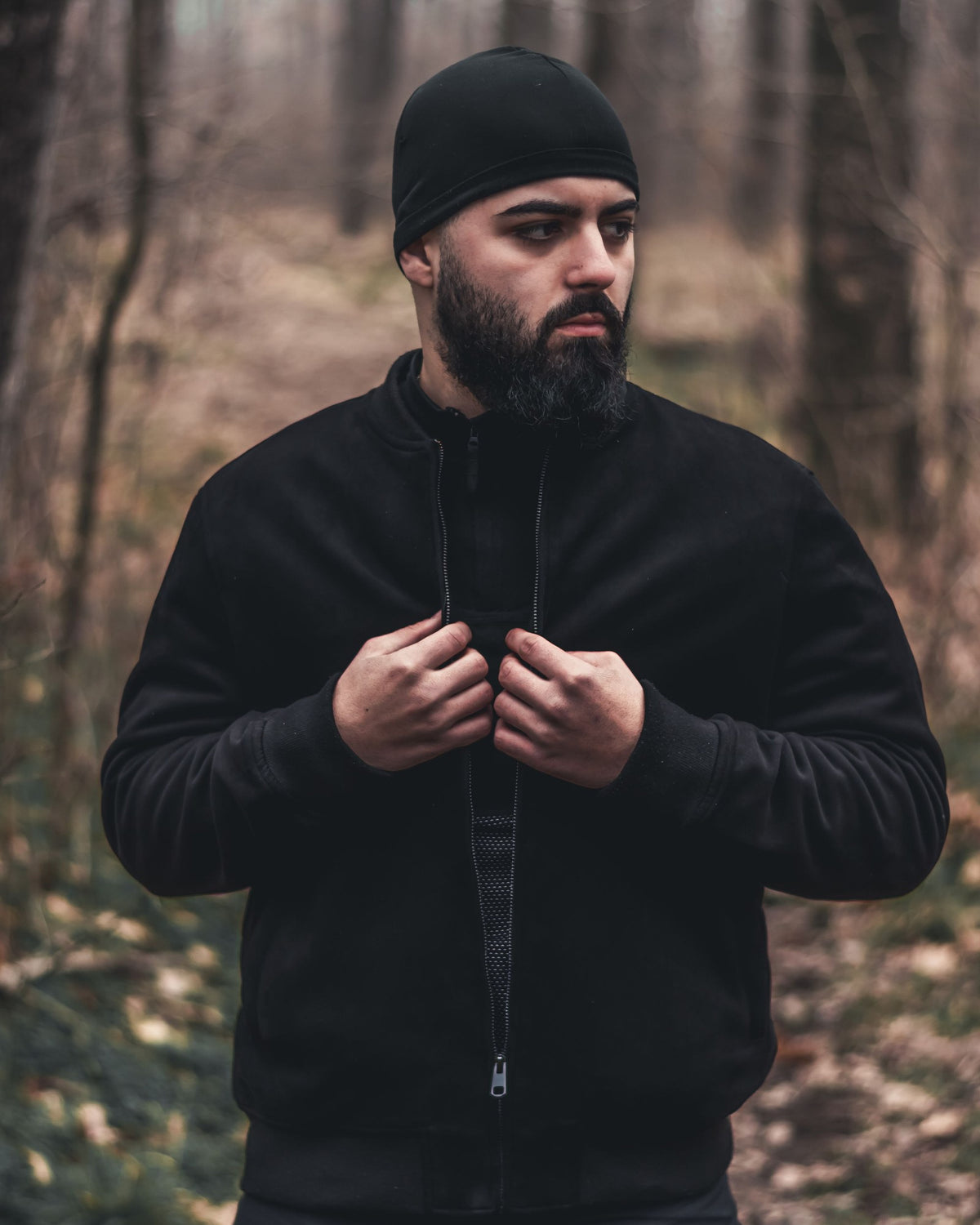 Mann in schwarzer Jacke mit Reißverschluss im Herbstwald